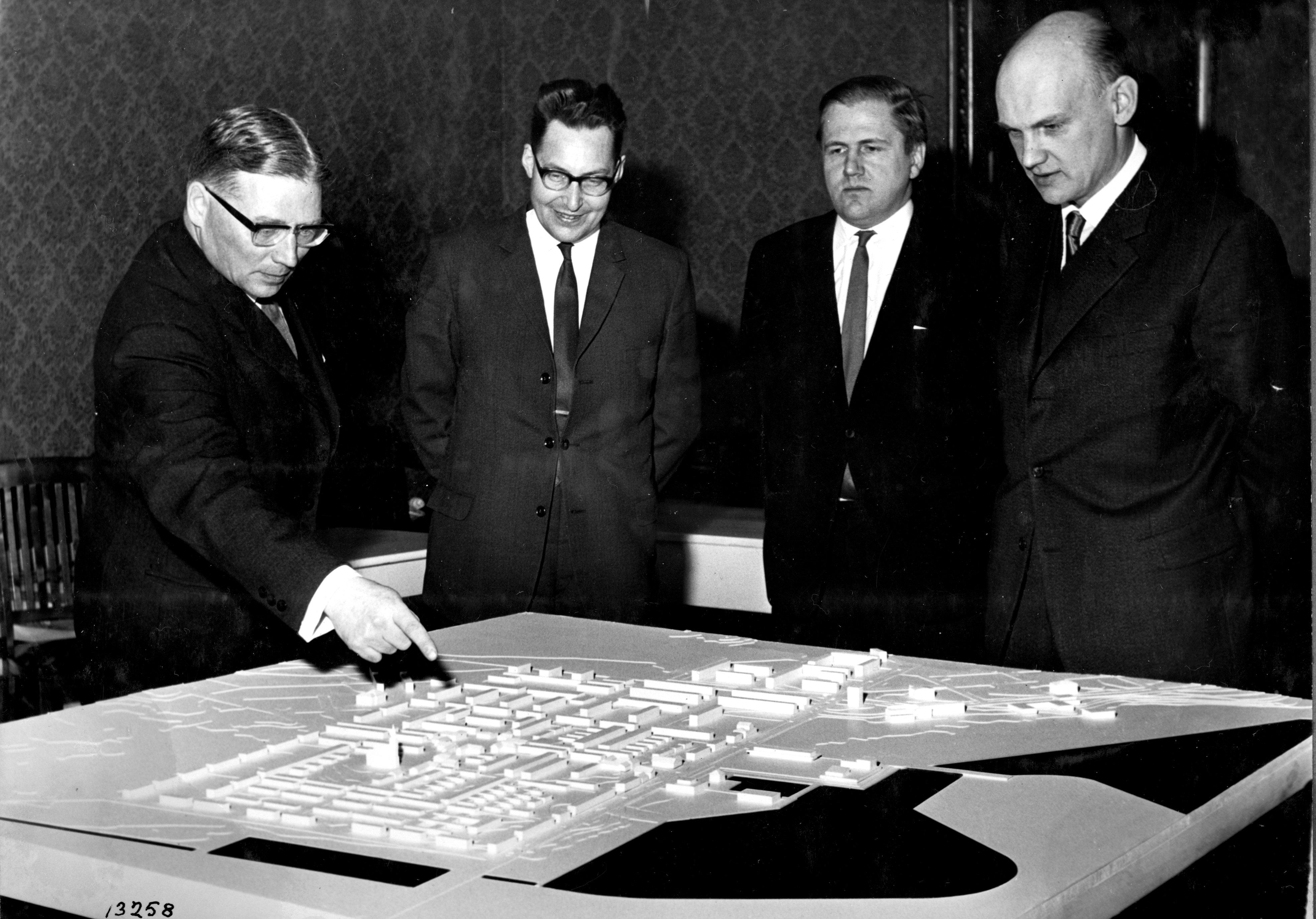 Neljä miestä seisoo Raahen keskustan suunnitelman pienoismallin äärellä.